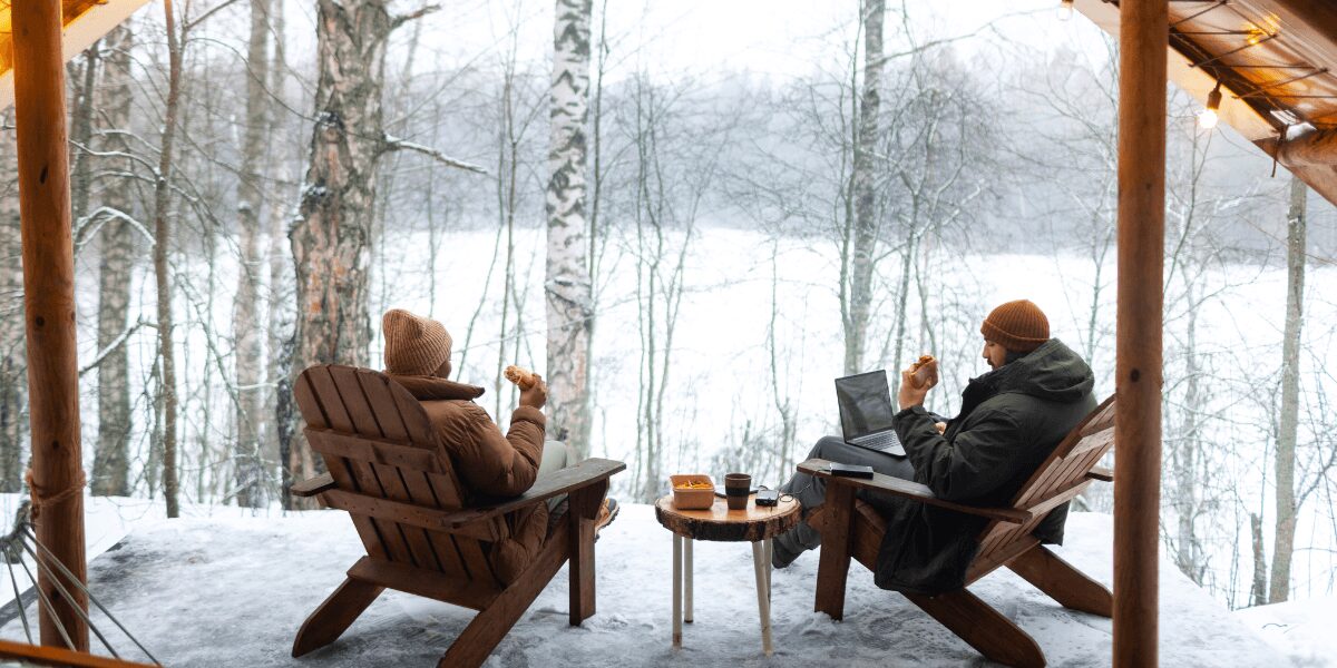 Two men sitting on chairs, enjoying a cup of tea together on a chilly winter day.