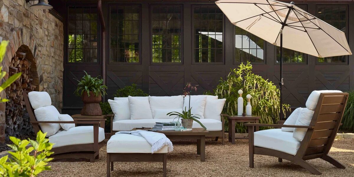 Ergonomic patio furniture set with white cushions, coffee table, and umbrella in a stylish outdoor setting, emphasizing comfort and back support for post-activity relaxation.