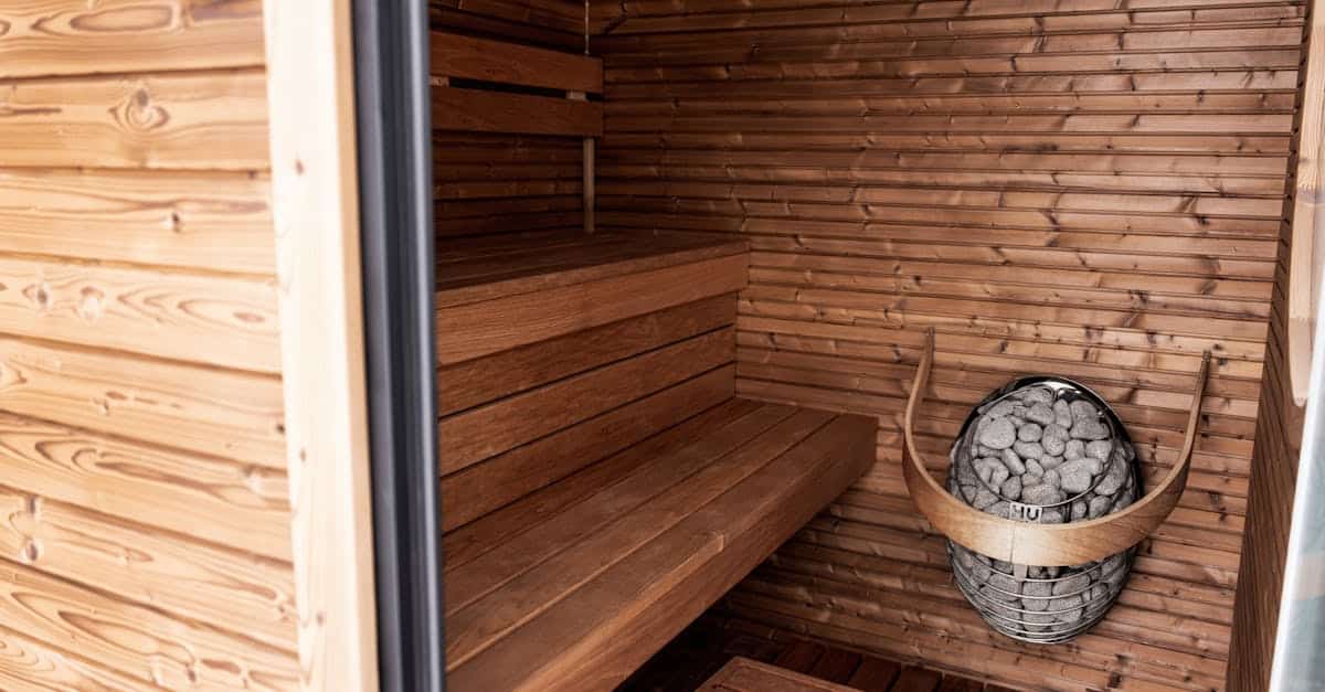Interior view of a traditional sauna featuring wooden benches, a stone basket for heating, and natural wood paneling, highlighting the relaxing environment for wellness and health benefits.